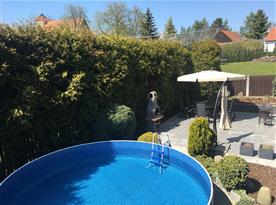 Pohled na bazén s posezením a zahradním grilem