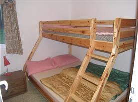Ložnice s patrovou postelí, stolkem, regálem a lampičkou