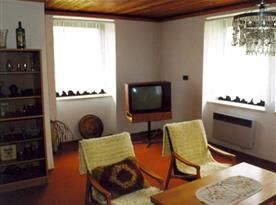 Obývací pokoj s pohovkou, stolkem, křesly a televizí