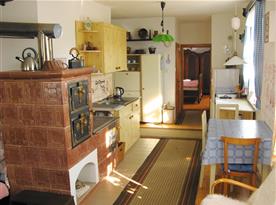 Kuchyně se sporákem, lednicí, varnou konvicí, stolem a židlemi, plně funkční kachlová kamna