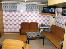 Společenská místnost se sedací soupravou, stolkem a televizí