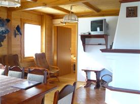 Osmilůžková chata - obytná místnost se stolem, židlemi, krbem a televizí