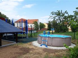 Zastřešené venkovní posezení s výhledem na bazén a trampolínu