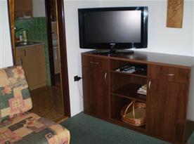 Obývací pokoj s 2x pohovkou, stolem, židlí, skříňkou a televizí