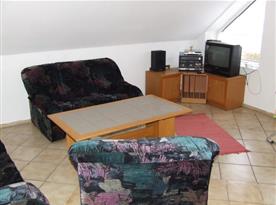 Obývací pokoj s televizí, sedačkou a hifi věží